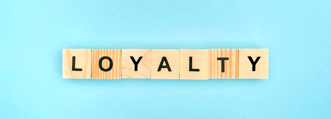 top view of loyalty lettering made of wooden cubes on blue background