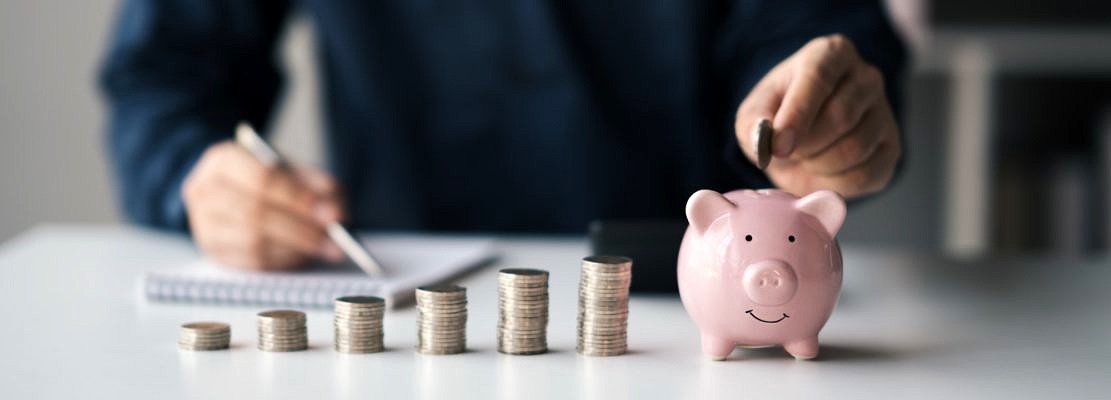 Businessman putting coins into piggy bank for saving money concept.