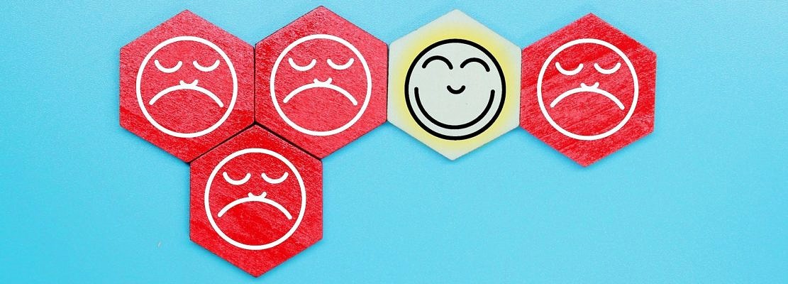 wooden hexagon with a sad face icon on a red wooden hexagon