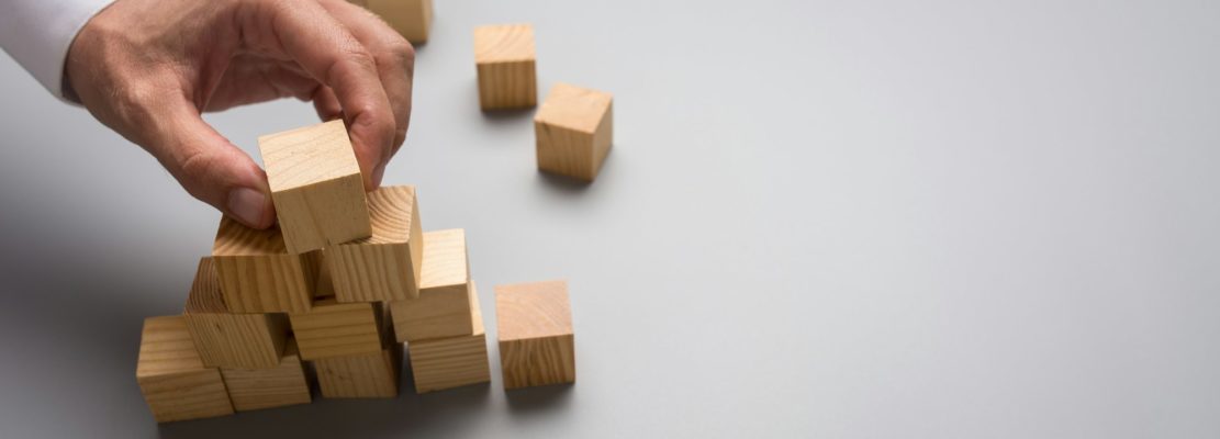 Businessman arranging wooden cubes in pyramid shape