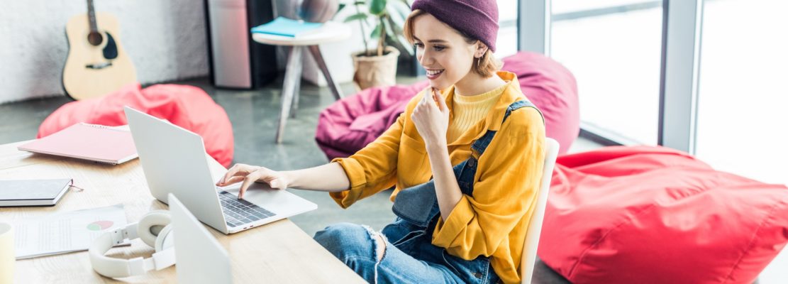 beautiful smiling young female it specialist using laptop in loft office