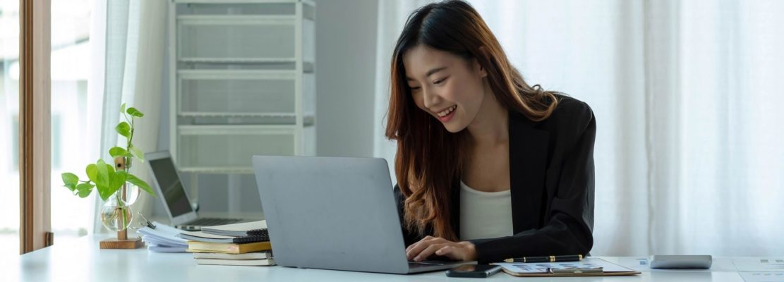 Charming asian businesswoman sitting working on laptop in office.