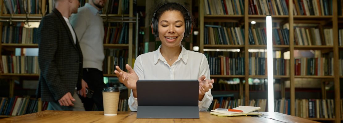 Female office worker wearing headphones working on laptop computer