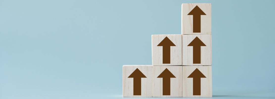 Group of brown arrows going up on wooden blocks and light blue background