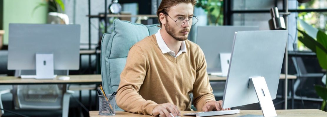 Serious and scorn-centered man in the office at work with a computer, man typing thoughtfully on