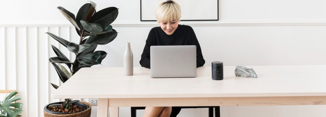 Woman working on her laptop with a blank frame hanging on a wall