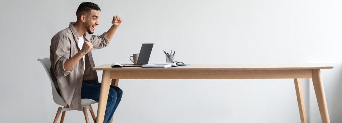 Arab man using laptop celebrating success shaking fists screaming yes