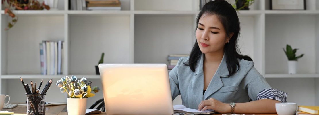 Asian business woman using laptop computer at office desk.