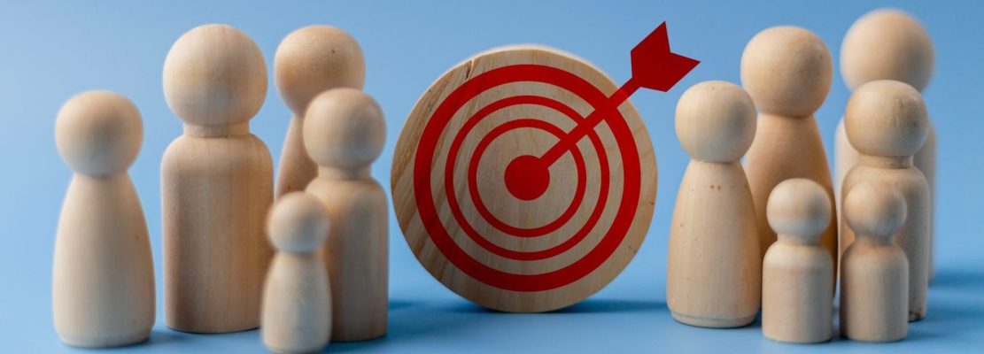 Business target concept. Wooden figures of people and a target on a blue background.