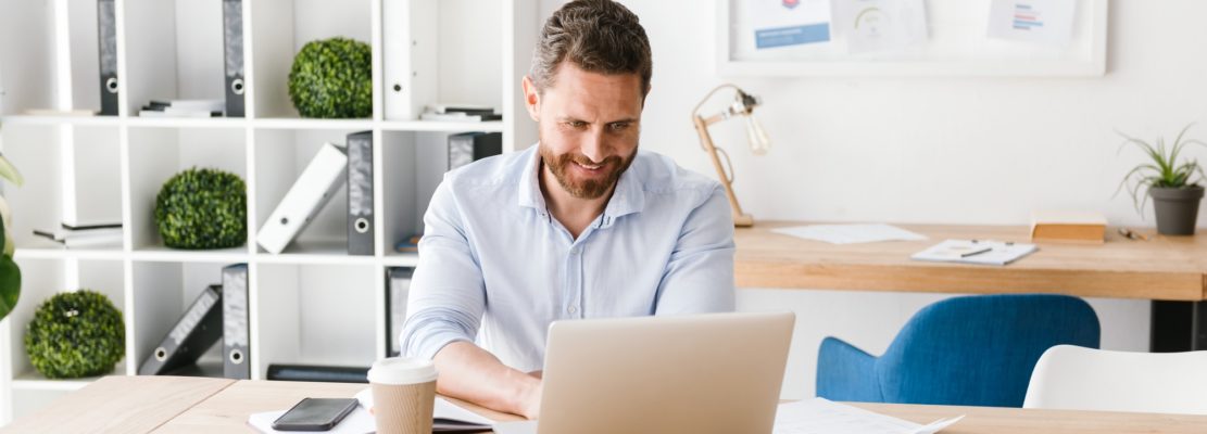 Happy bearded man sitting in office working