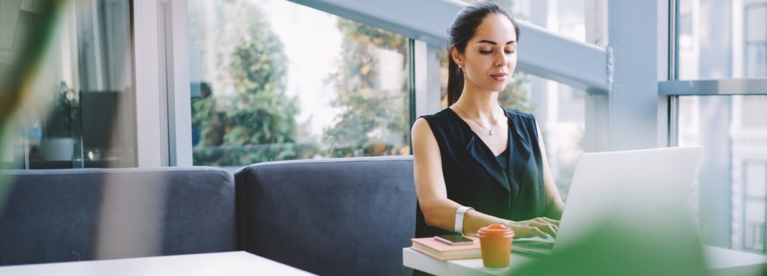 Thoughtful woman with laptop in modern workspace
