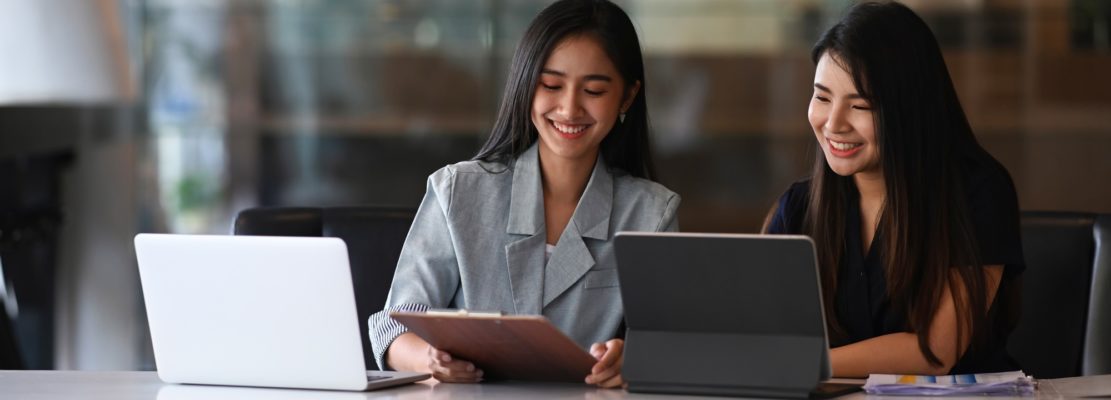 Two businesswoman working on tablet computer and discussing business data at modern office.