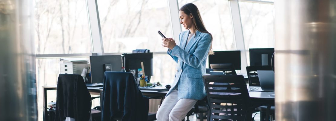 Woman using smartphone while sitting on table in office