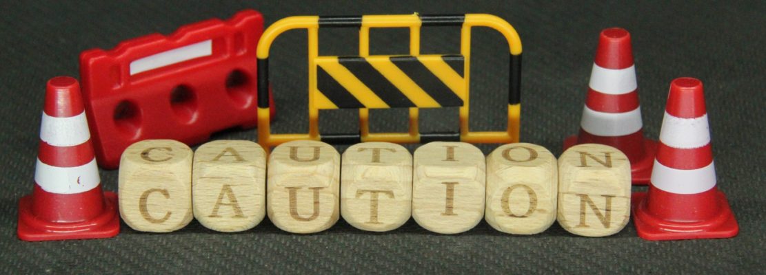 maintenance cones and words of caution on wooden cubes with blurred backgrounds