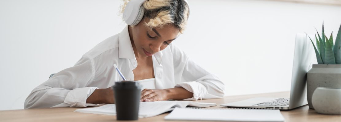 E-learning,online education concept.Happy student in headphones writing down lectures,doing homeworl