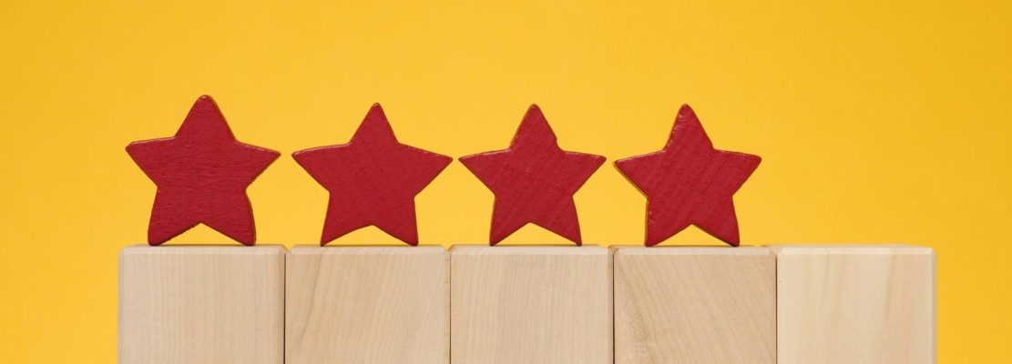 Four stars on wooden cubes, yellow background. Service evaluation concept, high rating