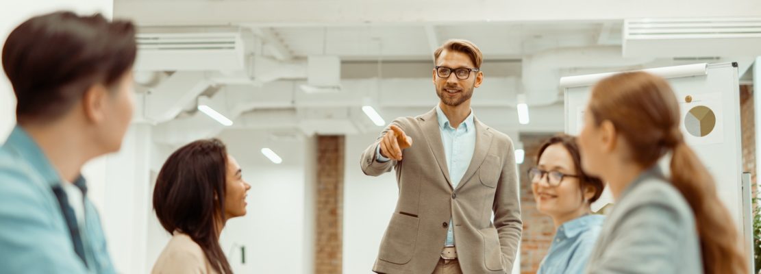 Leader standing in office and explaining new ideas to colleagues