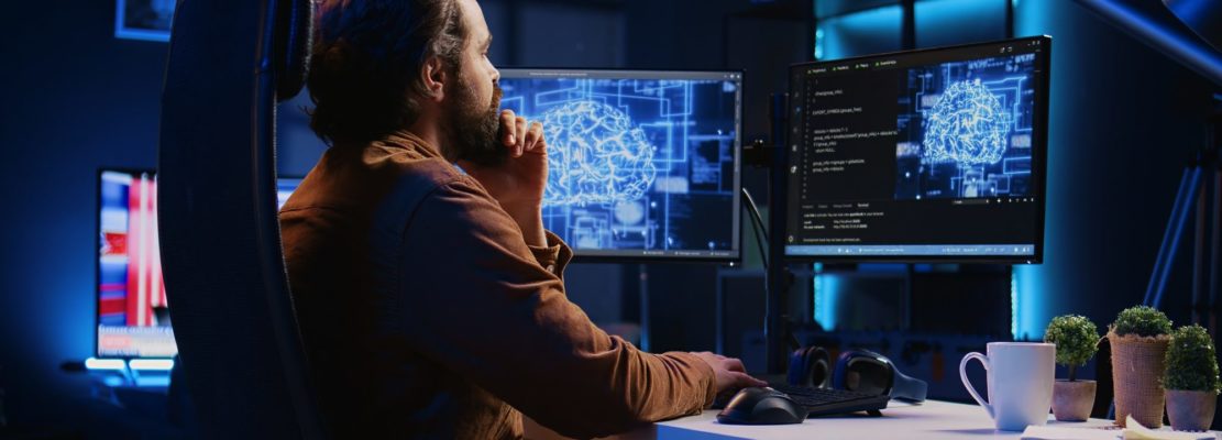 Freelancing programmer writes artificial intelligence code on desktop PC