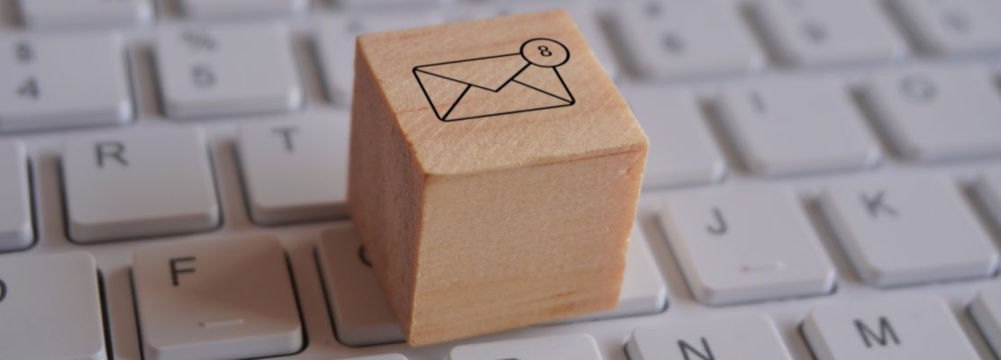 Wooden cube with new email notification icon on top of keyboard.